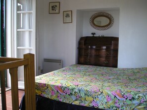 Un dormitorio con cama, cómoda, radiador y un espejo en la pared.