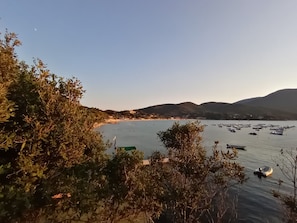 A coastal view with boats, a beach, and hills in the distance.