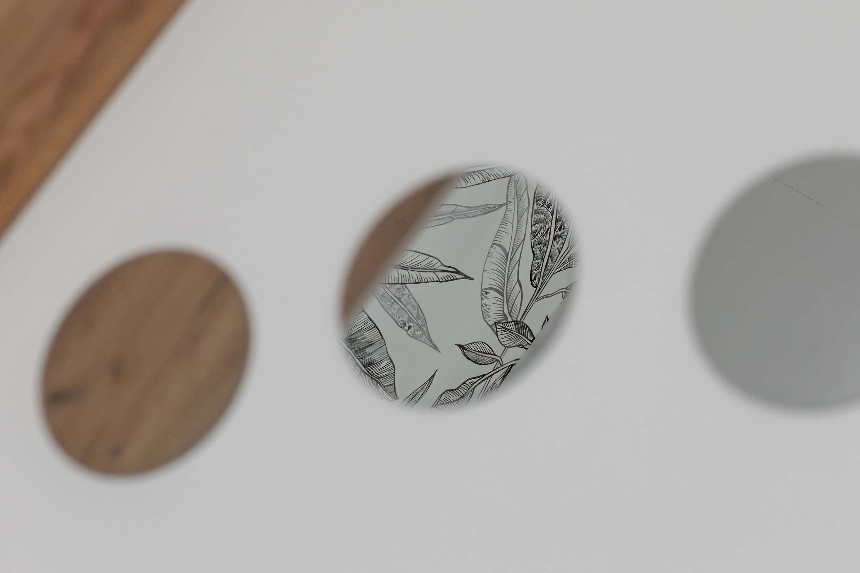 Trois objets circulaires aux motifs différents : l’un orné d’un motif de feuille, l’un uni et l’autre avec un motif imitant le grain du bois.