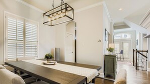Un espace repas comprenant une longue table, des chaises et un luminaire suspendu.