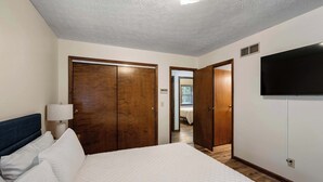 Une chambre d’hôtel avec un lit, une armoire en bois et un téléviseur fixé au mur.