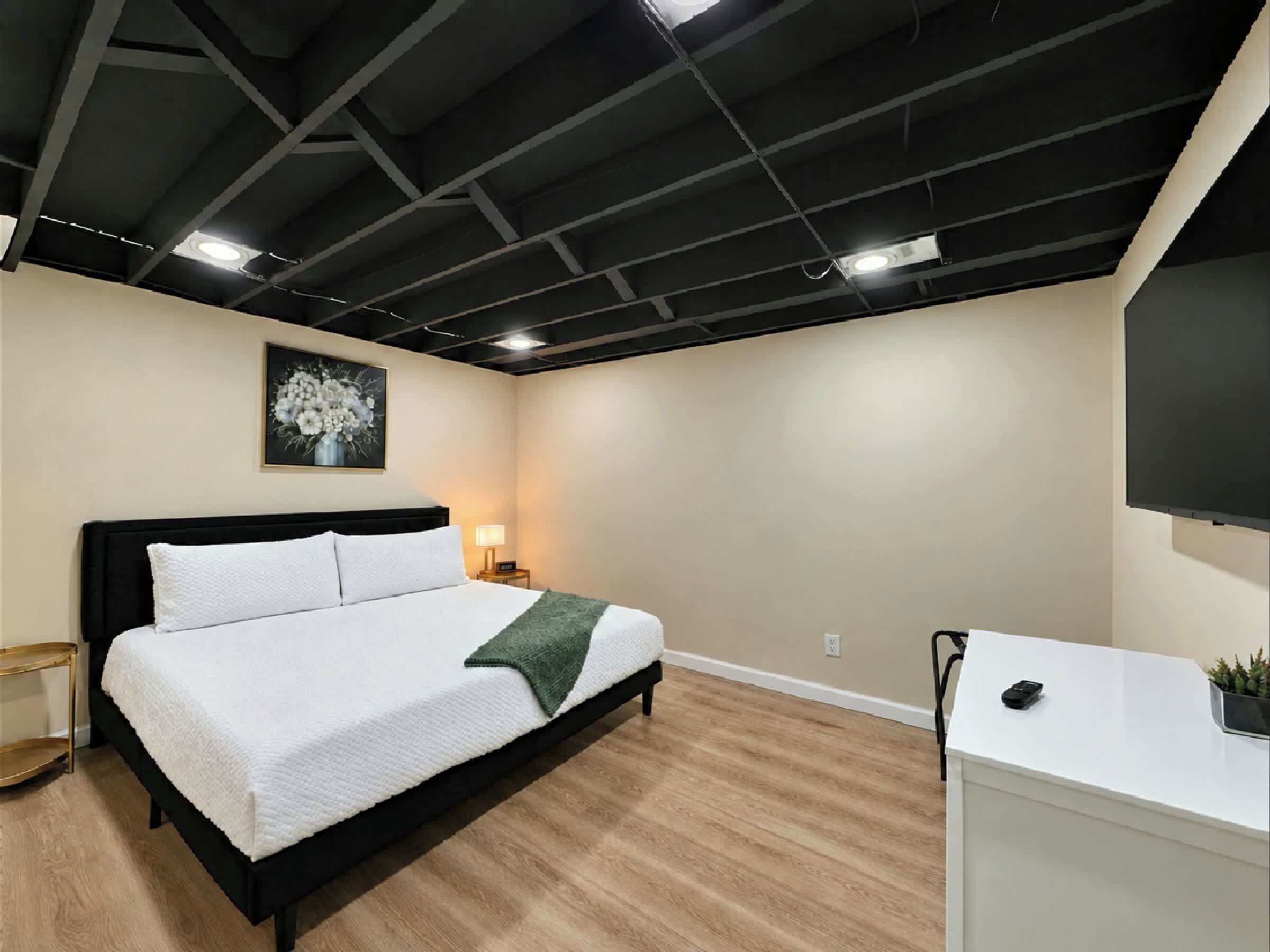 A modern hotel room with a bed, bedside table, lamp, and a flat-screen TV.