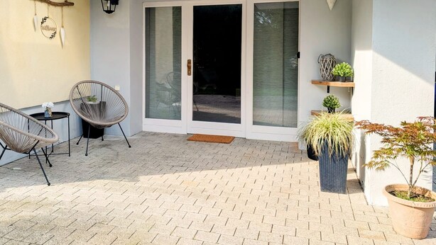 Un patio con dos sillones de mimbre, una mesita y una planta en maceta.