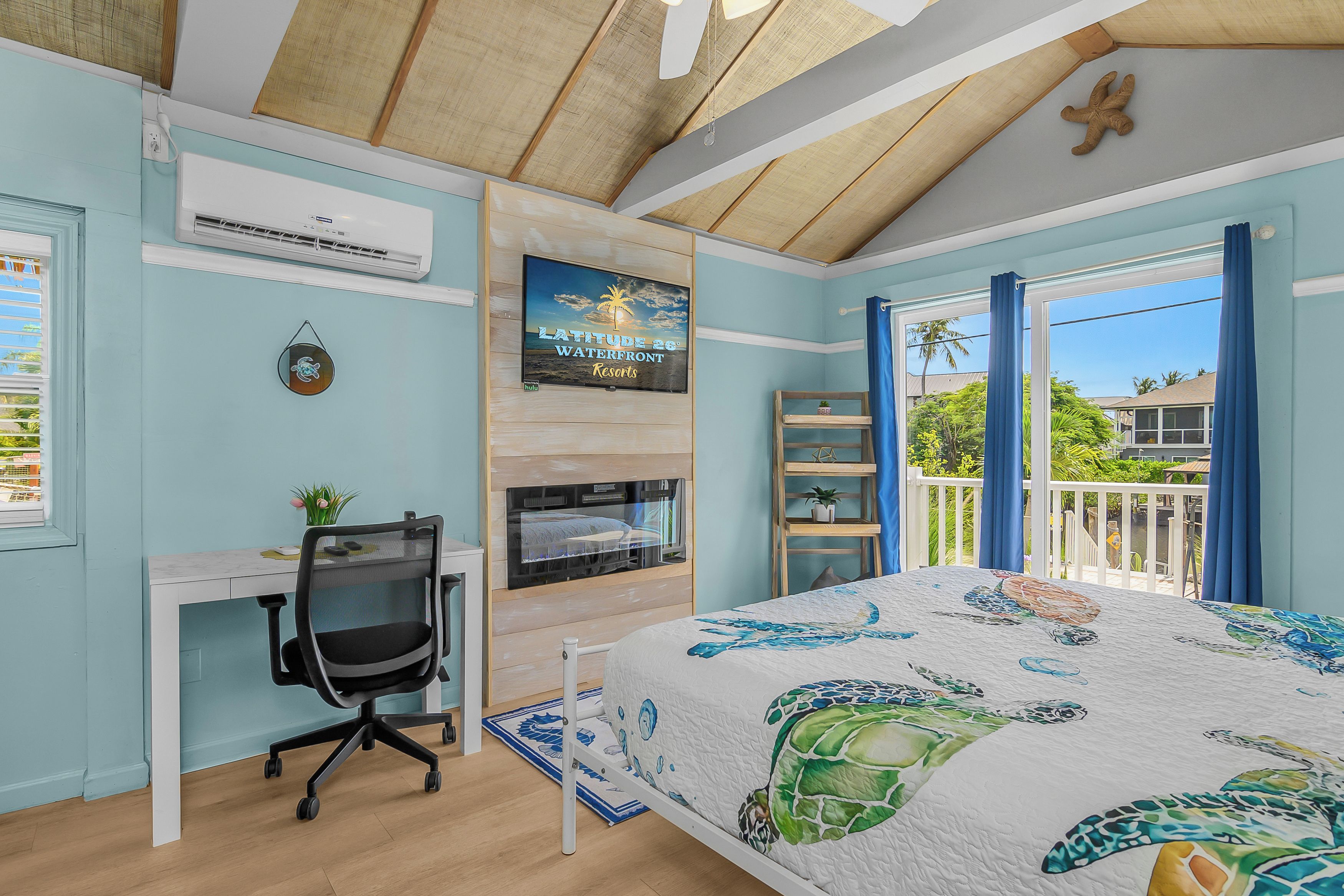 Un dormitorio con cama, escritorio, silla y televisor en la pared.