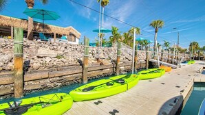 A dock with kayaks, a pool, and a thatched-roof structure. - Waterfront Coconut Cottage in Fort Myers Beach (Fort Myers Beach)