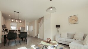 Un salon moderne comprenant un canapé, une table basse et un coin repas avec des chaises.