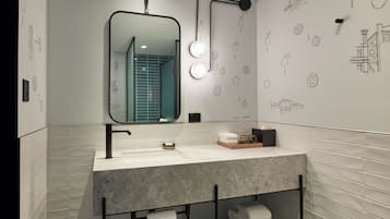 Un baño moderno con un espejo grande, un perchero para toallas y un lavamanos.