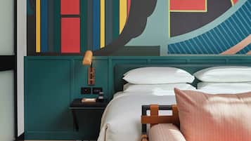 Un dormitorio moderno con cama, mesita de noche y un colorido mural abstracto en la pared.