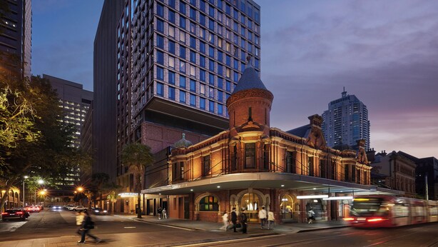 Un hotel con una facciata in vetro moderna e un edificio storico con una cupola e finestre ad arco.