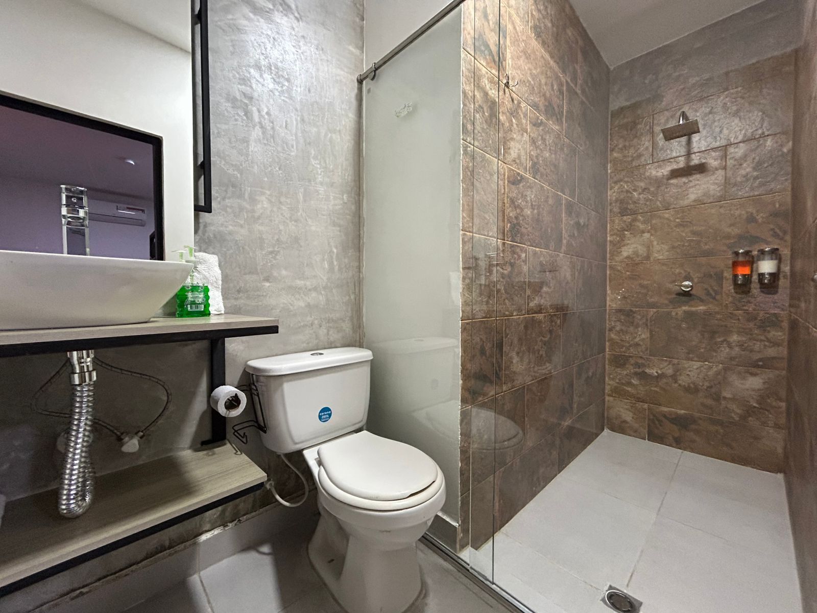 Un baño moderno con inodoro, lavabo y zona de ducha.
