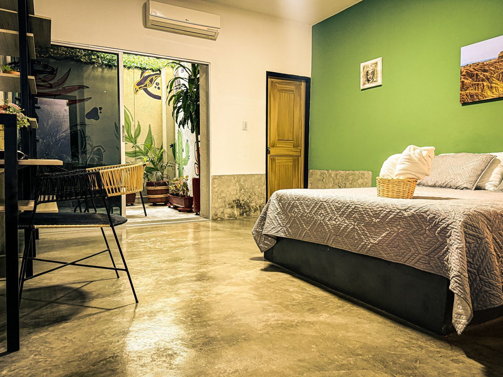 A room with a bed, a chair, a table, and a door.