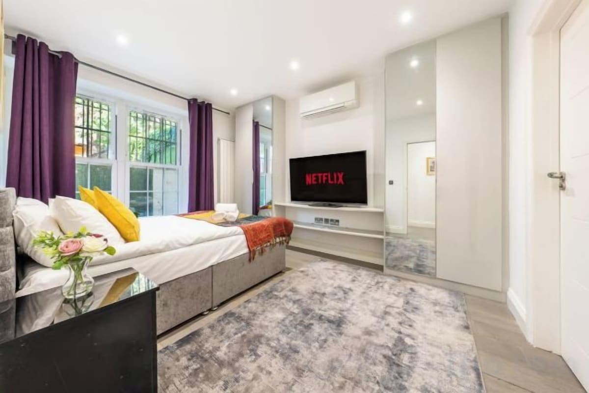 A modern bedroom with a bed, TV, and a large window.