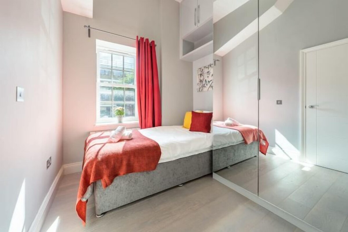 Un dormitorio moderno con una cama, una ventana con cortinas, una obra de arte en la pared y una puerta.