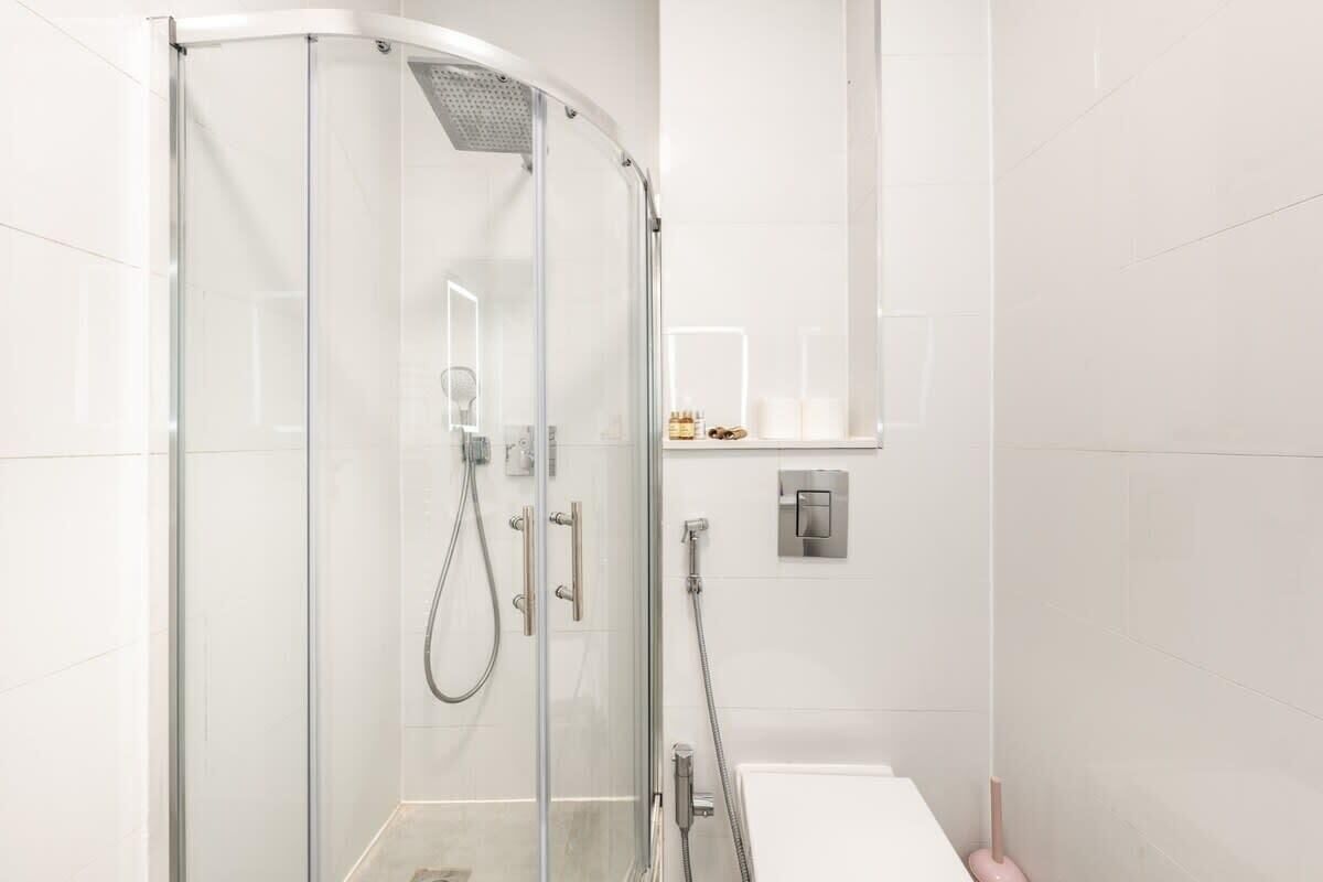 Une salle de bain moderne avec une douche à parois de verre, un lavabo blanc et un miroir.