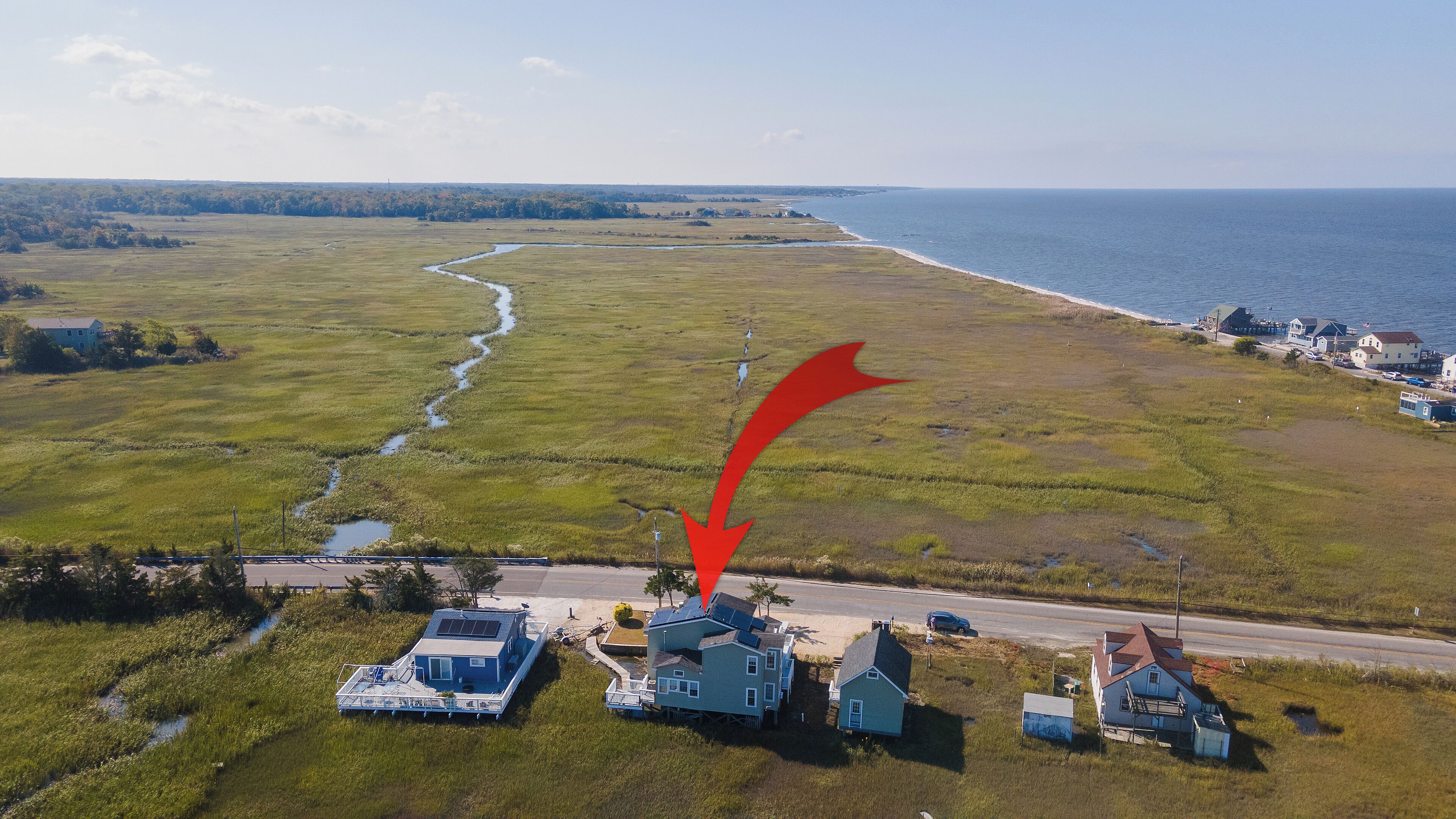 An aerial view of a coastal area with a houseboat, a road, and a small settlement near the water.