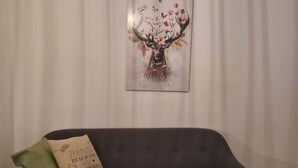 Un sofá gris con un cojín y una obra de arte enmarcada de un ciervo con astas y flores.