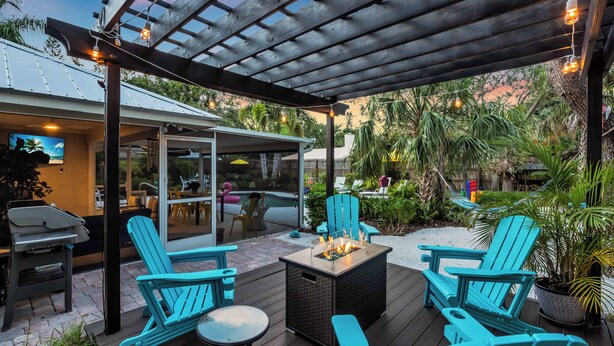 An outdoor patio with Adirondack chairs, a fire pit, and a pergola.