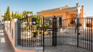 A gated entrance with a metal gate, a paved walkway, and a building with a beige facade.
