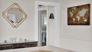 A room with a large wooden table, a wall-mounted mirror, and a world map artwork. - Coastal Cottage near Winery (St. Augustine)