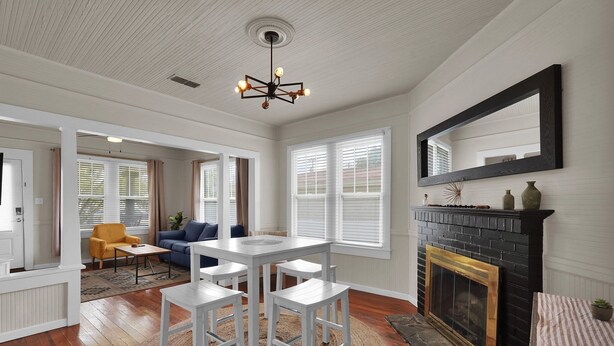 A spacious living room with a fireplace, white walls, and a large mirror. - Coastal Cottage near Winery (St. Augustine)