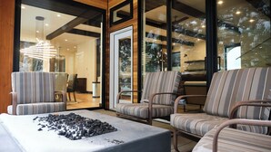 Una sala de estar moderna con chimenea de piedra, sillones a rayas y un ventanal que da a un comedor.