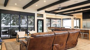 Una sala de estar moderna con un sofá de cuero, ventanas amplias y una zona de cocina.