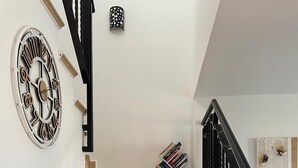 A staircase with beige steps, a black railing, and a wall-mounted clock.