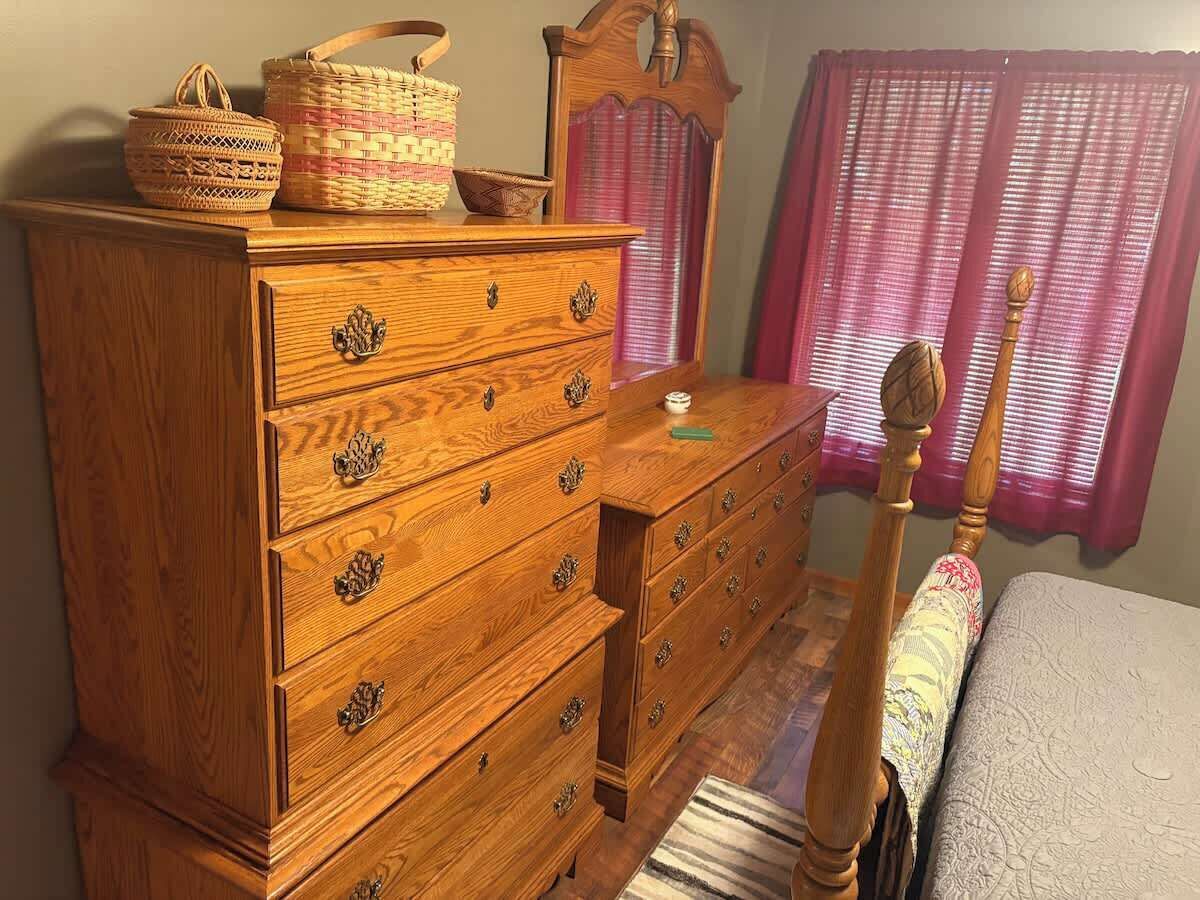 A wooden dresser with multiple drawers and a mirror above it. There are baskets on top of the dresser.
