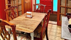 Un comedor con una mesa y sillas de madera, una puerta roja y una ventana con vistas.