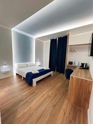 A modern hotel room with a bed, bedside tables, a desk, and a shower area. - Maison butera (Palermo)