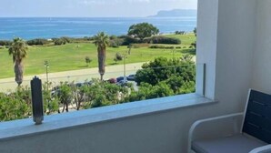Un balcón con vista al mar, una silla y suelo de baldosas.