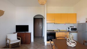 A compact living space with a kitchenette, a dining area, and a television.