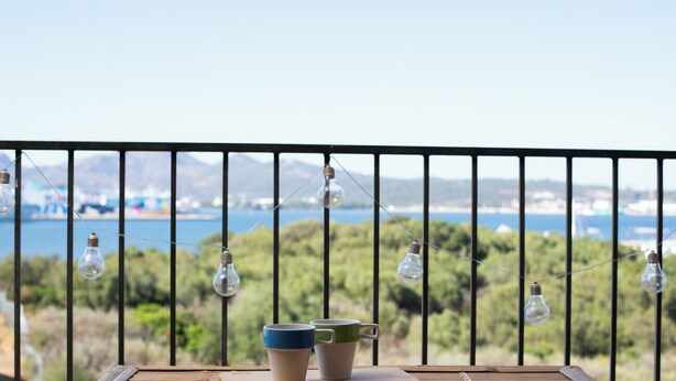 A balcony with a railing, two cups, and hanging light bulbs.