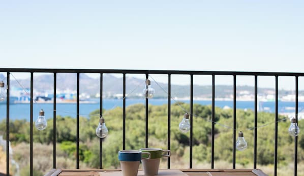 A balcony with a railing, two cups, and hanging light bulbs. - Studio Boho by Propertize  - sea view Olbia (Olbia)