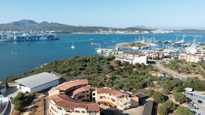 A coastal town with a marina, buildings with curved roofs, and a large ship docked at the harbor.