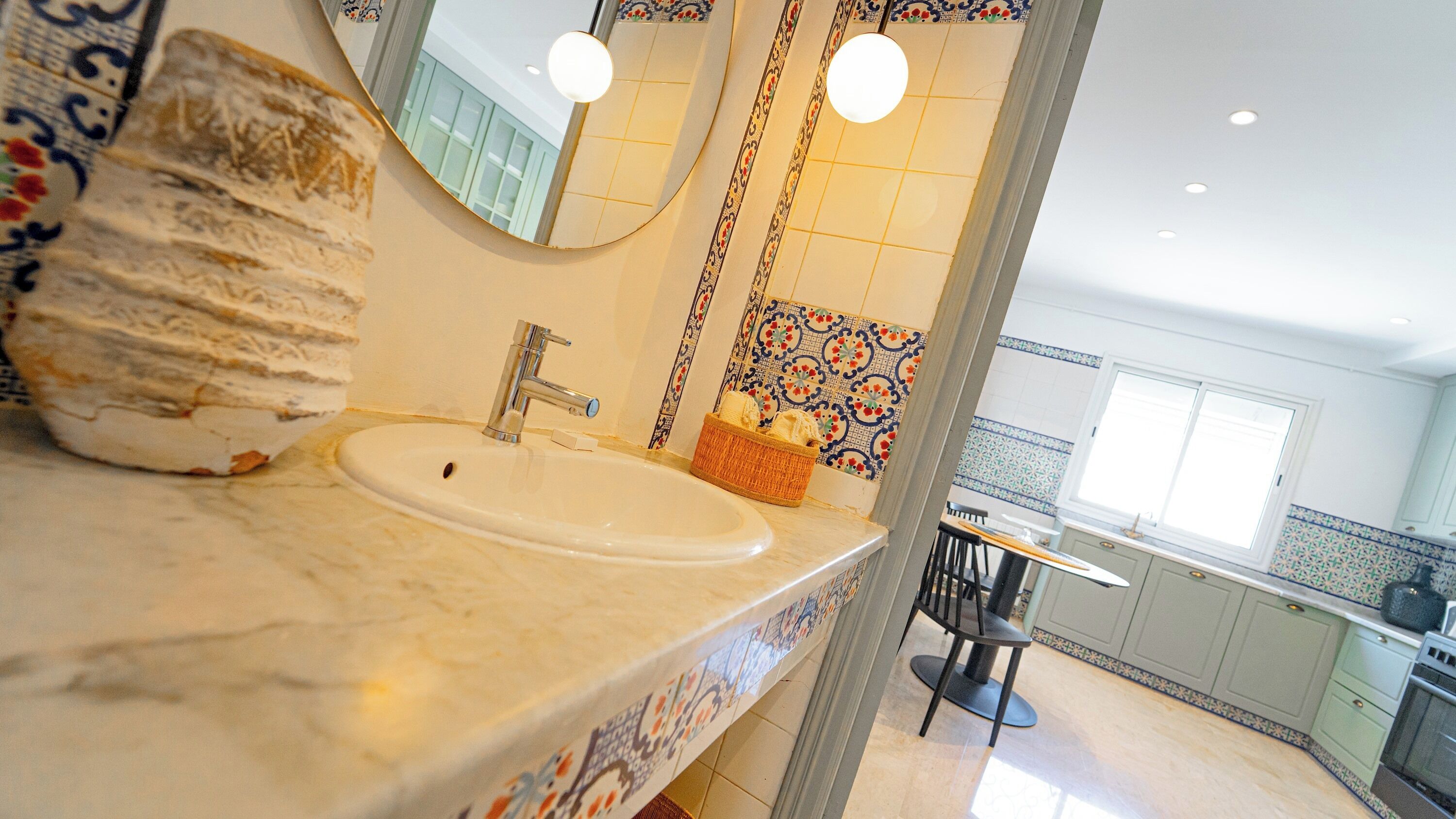 A bathroom with a marble sink, a mirror, and a decorative wall.