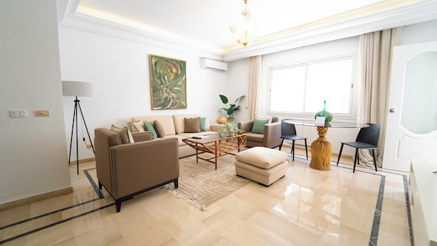 A modern living room with a sofa, coffee table, and a dining table with chairs. - Havre de Paix Apt en Plein Centre de la Marsa (La Marsa)