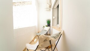 A small balcony with two chairs, a potted plant, and a window. - Havre de Paix Apt en Plein Centre de la Marsa (La Marsa)