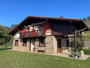 A stone building with a balcony, red doors, and a wooden porch.