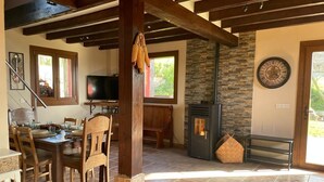 A dining area with a wooden table and chairs, a television, and a stone fireplace. - Chalet 'Txatonea' with Mountain View, Private Terrace and Wi-Fi (Uribarri-Zabaleta)