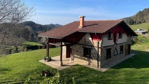 A stone house with a red roof, a chimney, and a covered porch. - Chalet 'Txatonea' with Mountain View, Private Terrace and Wi-Fi (Uribarri-Zabaleta)