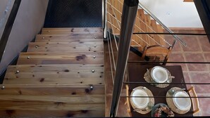A wooden staircase with a metal railing, a stained glass window, and a dining table set with plates and cutlery. - Chalet 'Txatonea' with Mountain View, Private Terrace and Wi-Fi (Uribarri-Zabaleta)