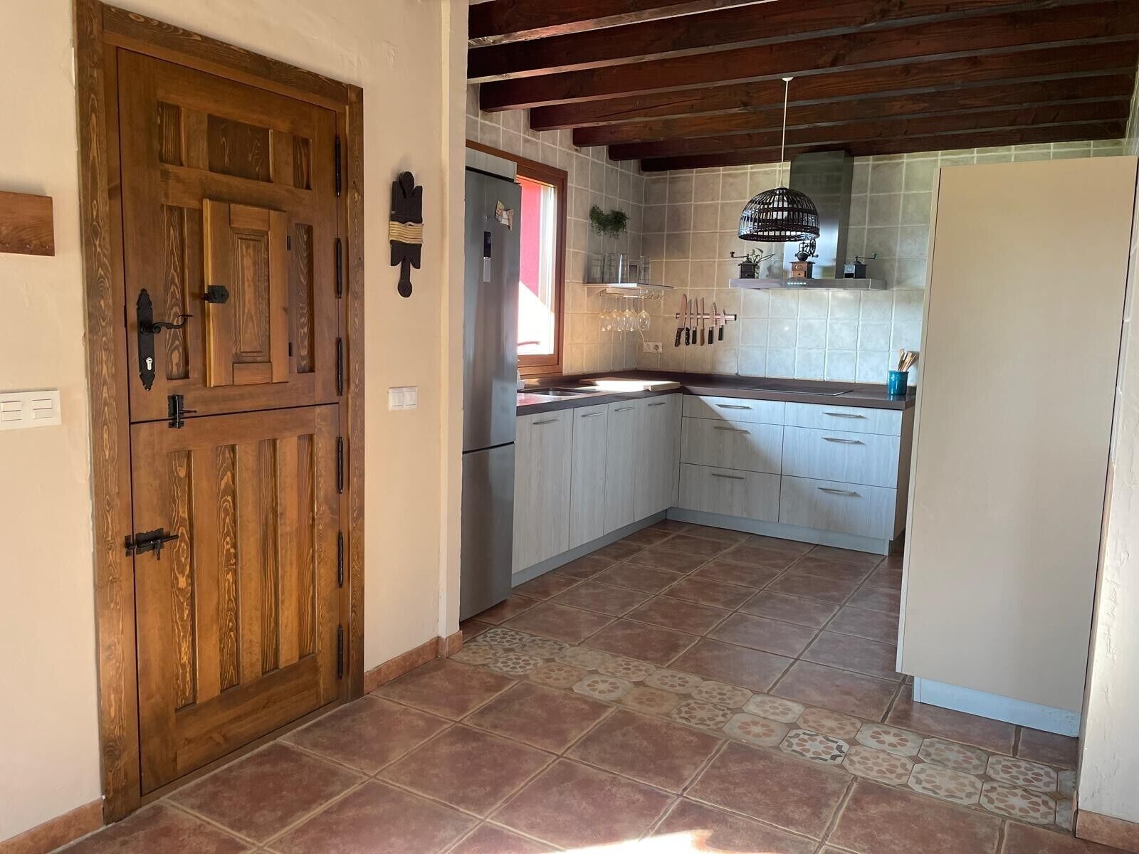 A kitchen with wooden cabinets, a refrigerator, and a tiled backsplash.