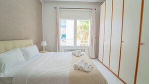A hotel room with a bed, a nightstand, a window with curtains, and a wardrobe.