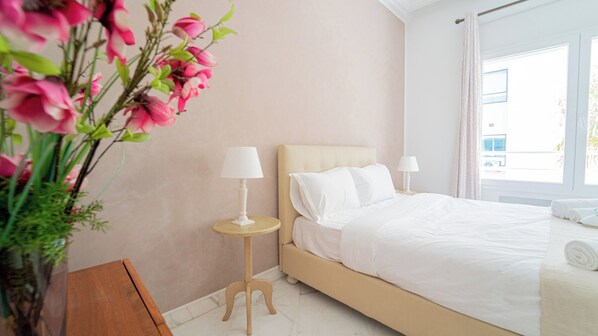 A hotel room with a bed, two bedside tables, a window, and a potted plant. - Infinity View Spacious 3 bd With Lake View (Tunis)