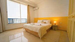 Habitación de hotel con cama, lámpara de noche, ventana con vistas y equipo de aire acondicionado.
