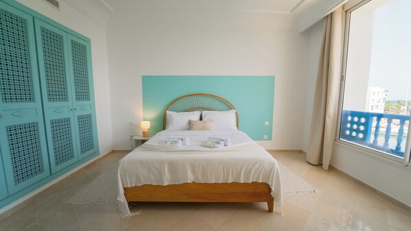 Habitación de hotel con cama, mesita de noche, ventana con vistas y armarios.