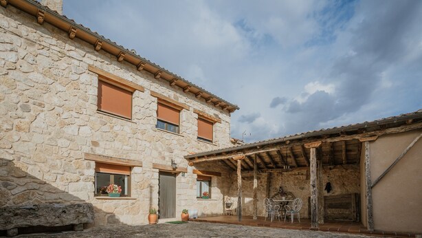 A stone building with a covered patio and outdoor seating area.