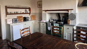 A kitchen with white cabinets, a wooden dining table, and a clock on the wall.