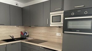 Una cucina moderna con mobili grigi, un forno nero, un microonde e un piano di lavoro in legno.